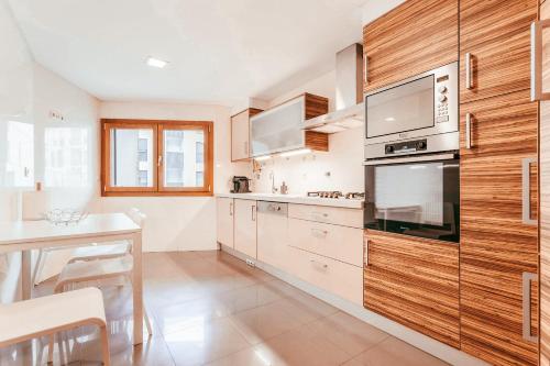 eine Küche mit Holzschränken, einem Tisch und einer Theke in der Unterkunft Modern & Elegant 2 bedroom in Amadora by GT House in Amadora