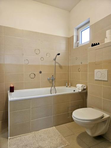 a bathroom with a tub and a toilet and a sink at Útulný apartmán s výhledem do kraje K J Erbena in Miletín