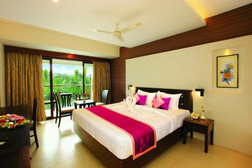 a bedroom with a large bed with pink pillows at Holiday Vista Thekkady a premium hotel near periyar wild life sanctuary with sky view pool in Thekkady