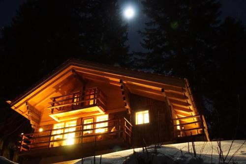 eine Blockhütte in der Nacht mit dem Mond im Himmel in der Unterkunft Wollhaus Oberzwirgi 6-Bettwohnung in Rohrmatten