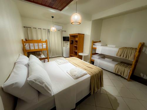 a bedroom with two beds and a bathroom at Pousada Kauai in Imbituba
