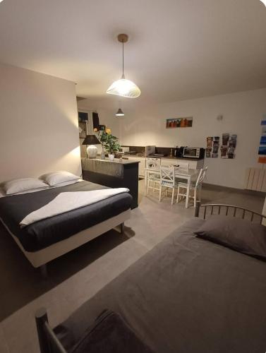 a bedroom with a bed and a kitchen with a table at Le Clos Doux in Céaux