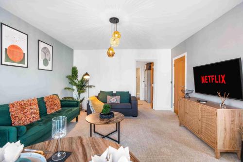 a living room with a green couch and a television at Queens Cove with Seaviews By My Getaways in Worthing