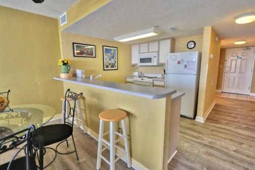 een keuken met een bar, een tafel en een koelkast bij Verandas 1107 in Myrtle Beach