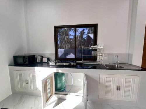 a white kitchen with a sink and a counter top at Grandma's Samui Garden - บ้านสวนคุณย่า in Ban Tai