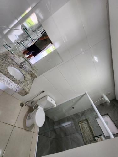 une salle de bains blanche avec toilettes et lavabo dans l'établissement Chácara de vidro, à Canindé de São Francisco