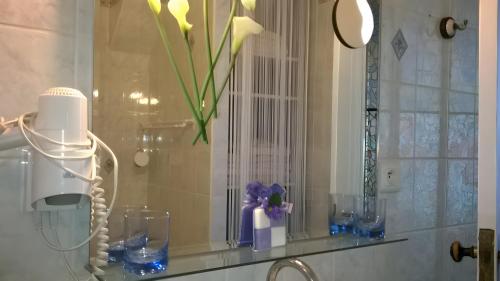 een plank met glazen en een vaas met bloemen erop bij Chambre La Petite Pause - Bordeaux in Bordeaux