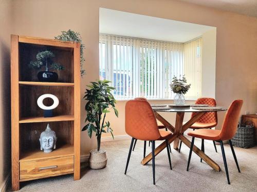 a dining room with a table and orange chairs at 3-Bedroom New Build House with Parking, Garden & Transport Links with Long Stay Offers in Thurcaston