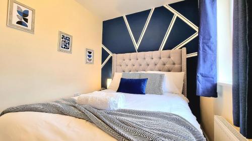 a bedroom with a large bed with a blue wall at 3-Bedroom New Build House with Parking, Garden & Transport Links with Long Stay Offers in Thurcaston