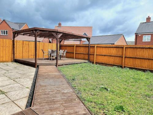a wooden gazebo with a table and chairs in a backyard at 3-Bedroom New Build House with Parking, Garden & Transport Links with Long Stay Offers in Thurcaston