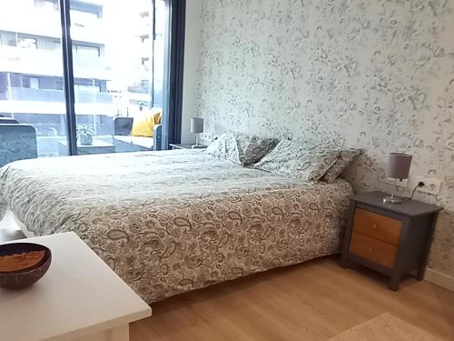 ein Schlafzimmer mit einem Bett und einem Tisch und einem Fenster in der Unterkunft Modern apartm near the beach and Barcelona in Masnou