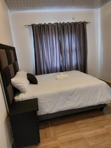 a bedroom with a large bed with a window at Mandy & Mos' Greenfields Cottage in Gaborone