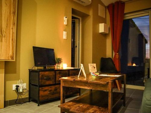 un salon avec une table et une télévision dans l'établissement Terrasse couverte et BBQ - Petite maison cosy, à Magnet