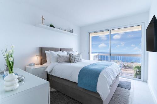 ein weißes Schlafzimmer mit einem großen Bett und einem großen Fenster in der Unterkunft Luxury Top Floor Sea View Downtown Cap d'Ail in Cap d'Ail