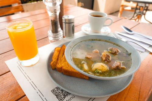 un tazón de sopa con pan y una taza de jugo de naranja en Unique Mine Luxury Lofts by Jalo, en Bogotá
