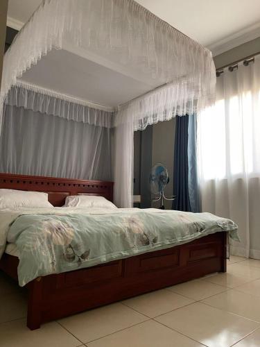 a bedroom with a large bed with a canopy at Carihaven Homz Najjera in Buwate