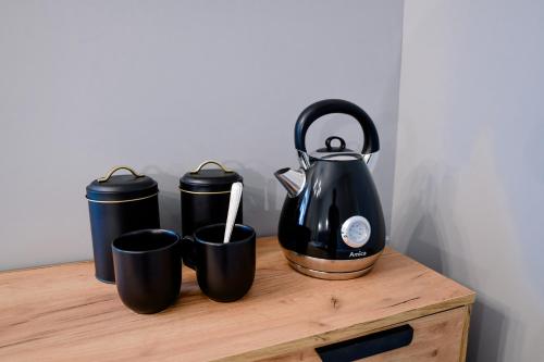a tea kettle and three cups on a wooden table at Bolero Apart in Tallinn