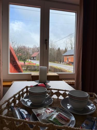 einen Tisch mit Schalen und Platten auf einem Tisch mit Fenster in der Unterkunft Kuća Šarenka in Kupjak