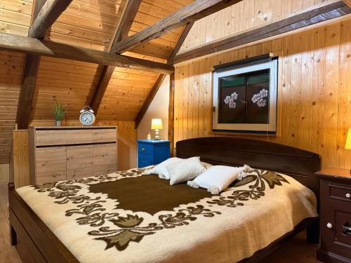ein Schlafzimmer mit einem großen Bett in einem Zimmer mit Holzwänden in der Unterkunft Kuća Šarenka in Kupjak
