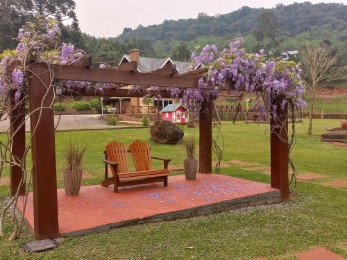 eine Pergola mit zwei Stühlen und einer Bank in der Unterkunft Palast Haus Pousada in Gramado