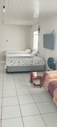 een witte kamer met 2 bedden en een raam bij Casa de hóspede turistas e Romeiro in Bom Jesus da Lapa