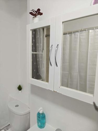 E1 Brick Lane Rooms في لندن: حمام ابيض مع مرحاض ونافذة