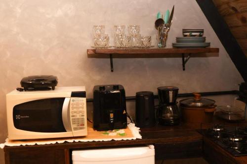 a kitchen counter with a microwave and glasses on a shelf at Cantinho do Vale# in Pomerode