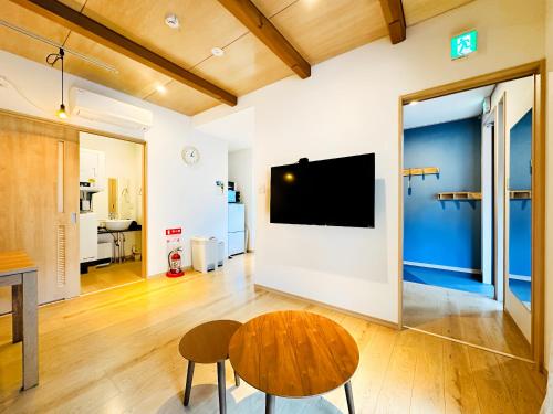 a living room with a table and a tv on a wall at Cozy Cove Hakuba in Hakuba