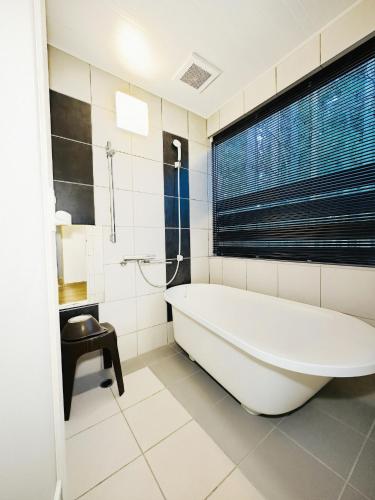 a bathroom with a white tub and a window at Cozy Cove Hakuba in Hakuba