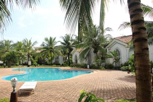 a pool in front of a house with palm trees at Riviera Hermitage in Anjuna