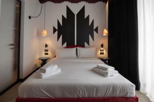 a bedroom with a large bed with two towels on it at Bazaar Hotel in Tirana