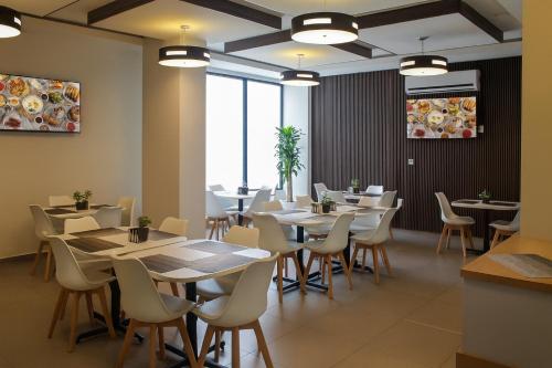 JM & Suites في سان لويس بوتوسي: غرفة طعام مع طاولات وكراسي بيضاء