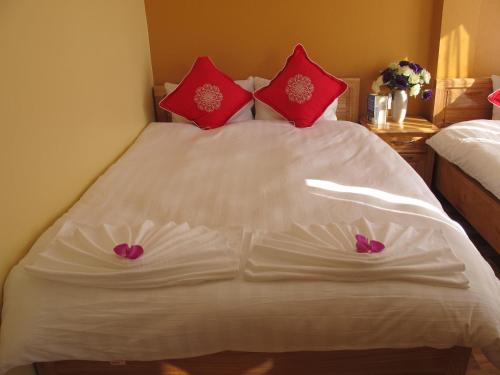 a white bed with red pillows and purple flowers on it at Sapa Backpacker Hostel in Sa Pa