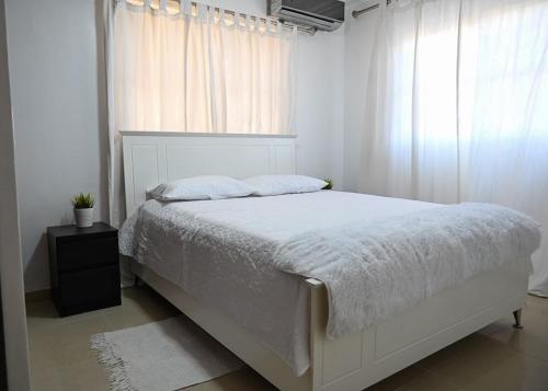 a bedroom with a white bed and a window at Bellomar I Exclusive Juan Dolio Playa Hemingway in Juan Dolio