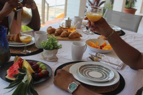 een groep mensen die aan een tafel zitten met eten en drinken bij Villa Caryota, Le Marin in Le Marin