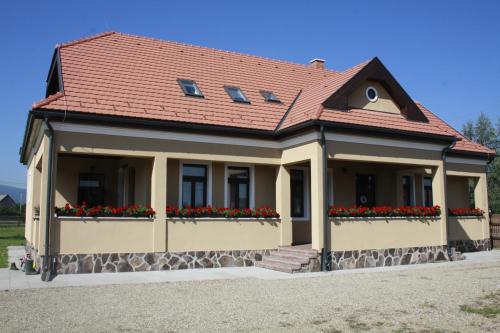 a house with a red roof and flower boxes at Pensiune AgroTuristica Horváth-Kert in Borzont