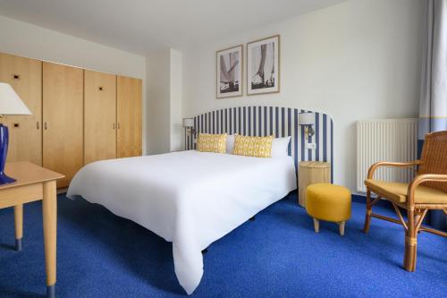 a bedroom with a large white bed and a desk and chair at IFA Rügen Hotel & Ferienpark in Binz