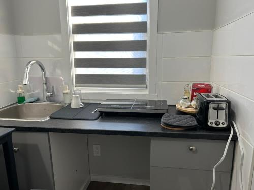 a kitchen counter with a laptop and a sink at 1BR suite, 20 minutes from the airport, with a kitchen in Edmonton