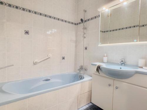 une salle de bain avec une baignoire bleue et un lavabo dans l'établissement Ty Corniche - 50m de la plage, à Bénodet