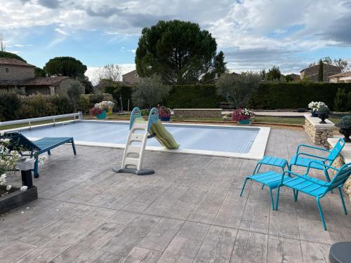 een zwembad met twee stoelen en een glijbaan naast een zwembad bij Villa Rube in Coustellet