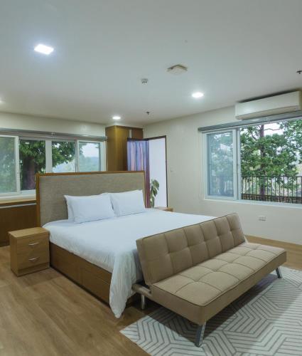 a bedroom with a bed and a couch and windows at Vine and Canopy in Olongapo