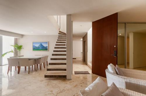 a living room with a staircase and a table and chairs at Magia beachside condos in Playa del Carmen