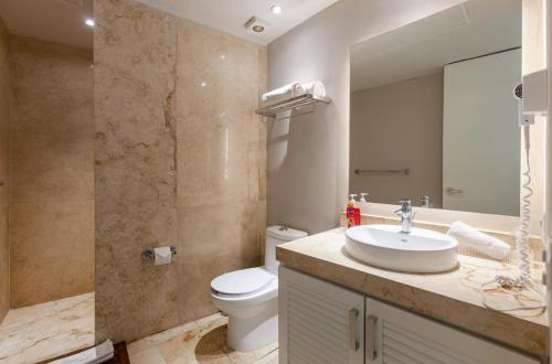 a bathroom with a sink and a toilet and a mirror at Magia beachside condos in Playa del Carmen