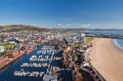 an aerial view of a city with a beach and boats at Salt House, Stunning Swansea Marina Townhouse Sleeps 12, Beach & Arena in Swansea