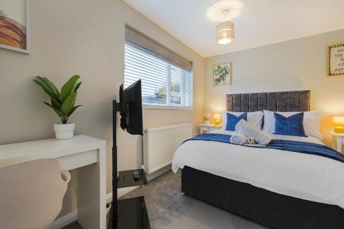 une chambre avec un lit avec des oreillers bleus et une télévision dans l'établissement Modern Comfort, Free Parking, Netflix & Disney plus in every Bedroom and Living Room, à Shephall