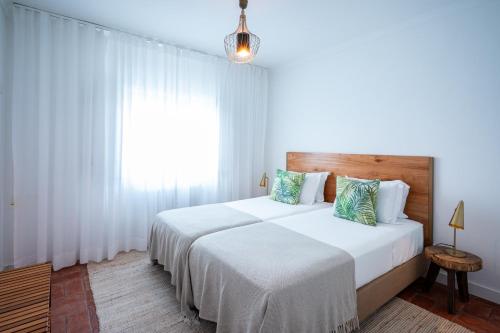 a bedroom with two beds and a window at Villa Eira in Vila Nova de Milfontes