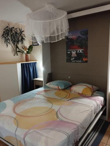 a bed in a bedroom with avertisementatronatronstrationstrationstrationstration at Studio Le Balisier in Caritan