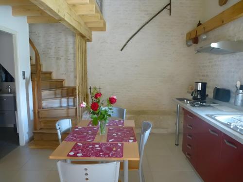 eine Küche mit einem Tisch mit einer Vase mit Blumen darauf in der Unterkunft Gite L'Etable in Saint-Hilaire-la-Palud