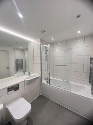 a bathroom with a toilet and a tub and a sink at 2 Bedroom Brentford in Kew Bridge