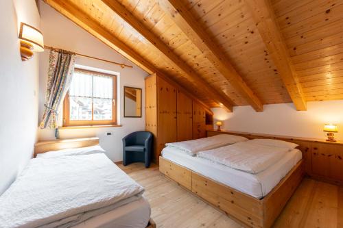 two beds in a room with wooden ceilings at Tobià de Barat in Pozza di Fassa